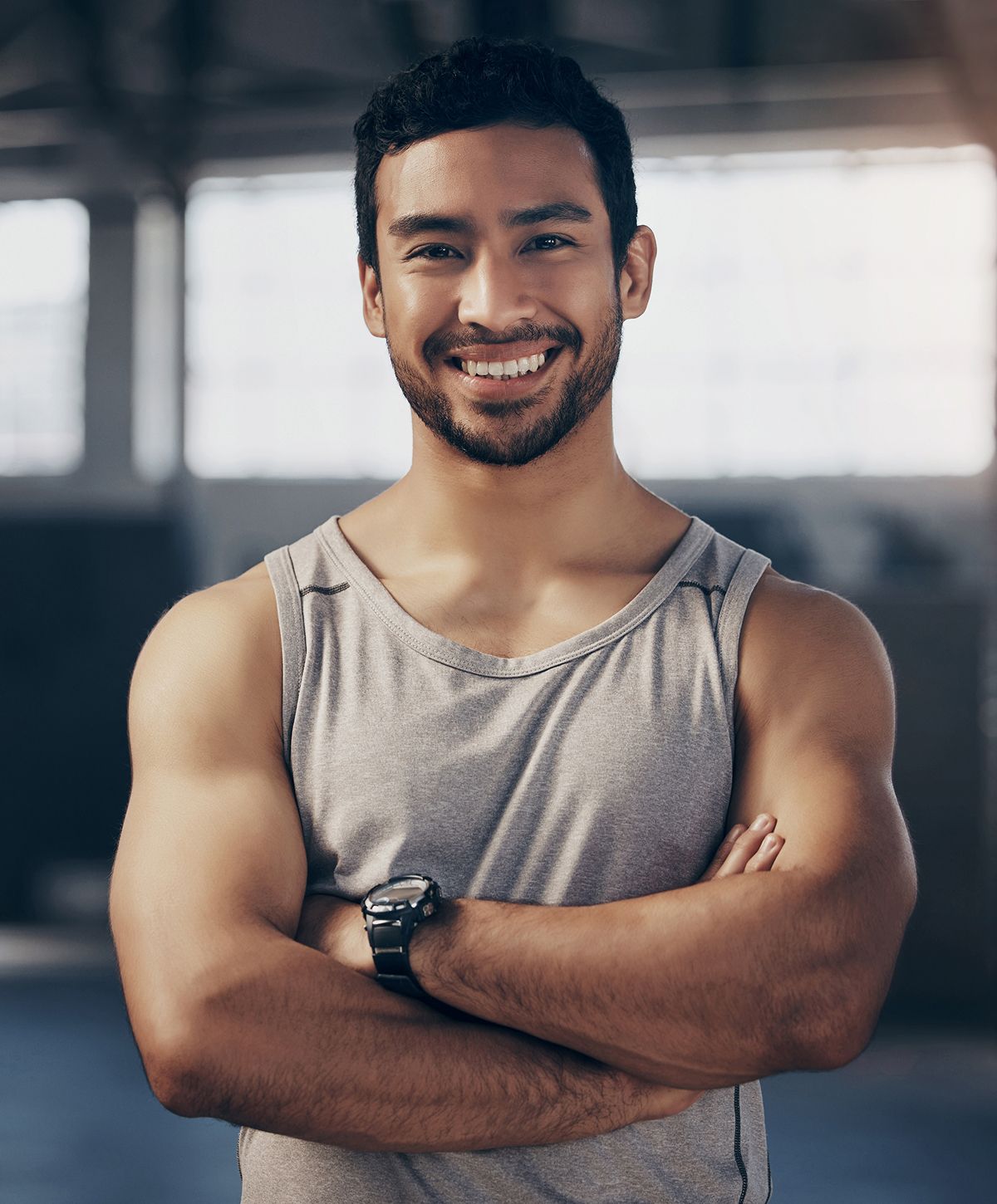 Smiling man with crossed arms in gym setting.
