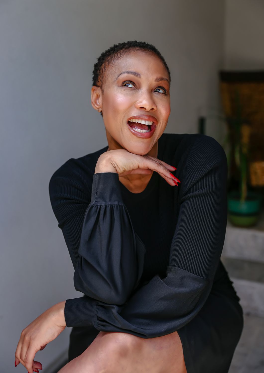 Woman smiling and posing playfully in black outfit.