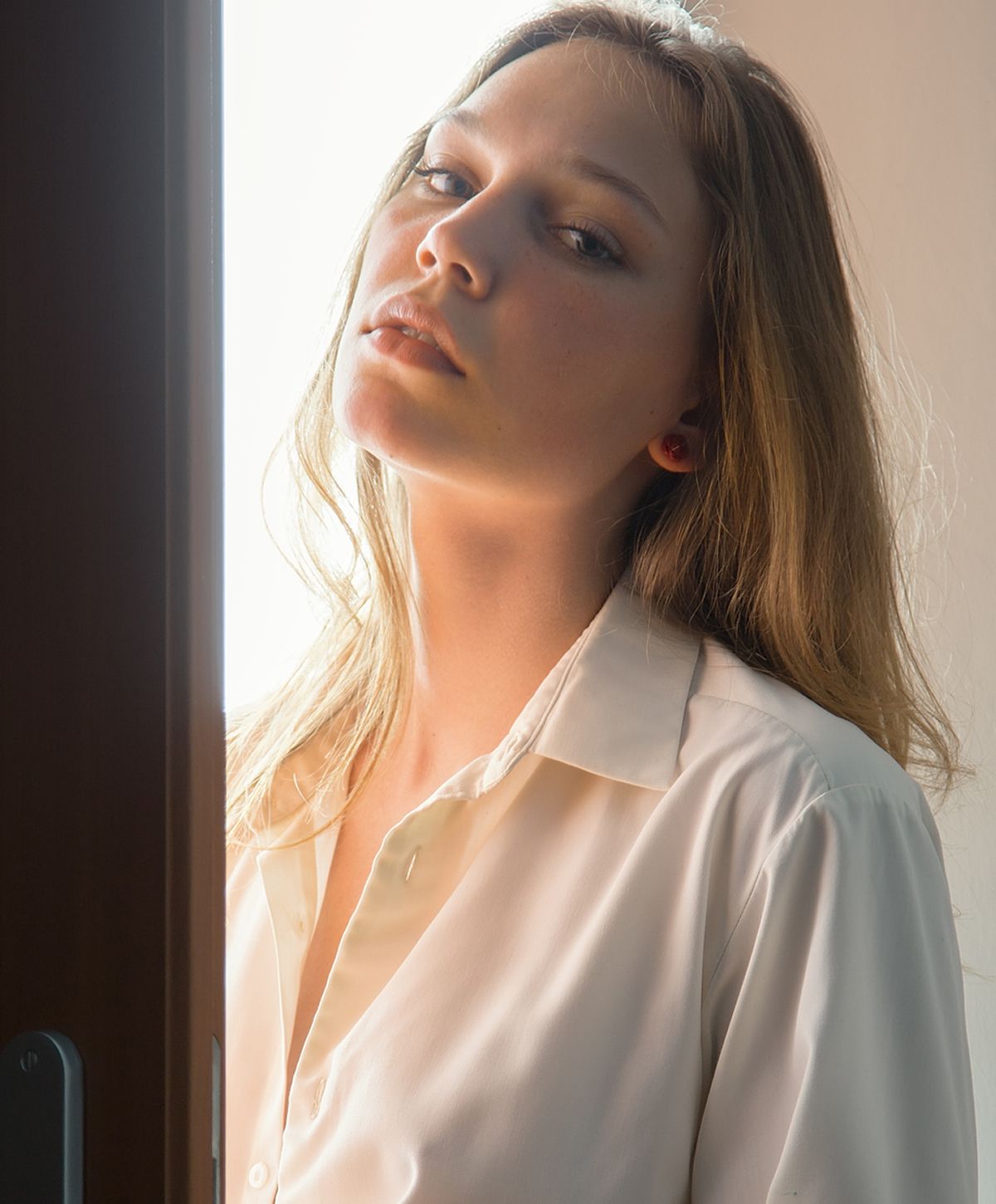 Woman with long hair near a window.