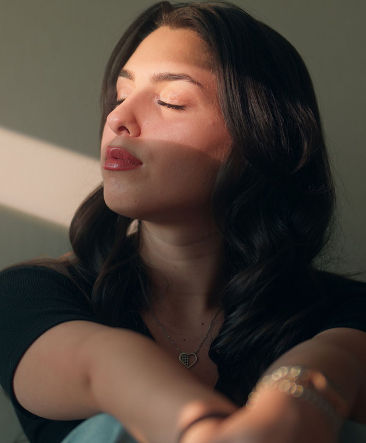 Smiling woman with wavy hair against gray background.
