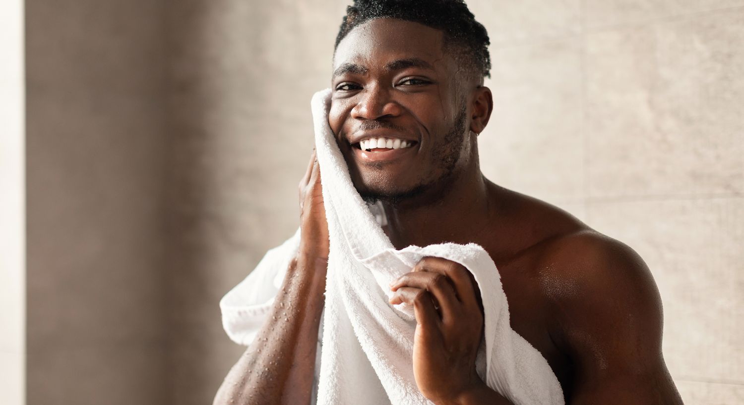 Smiling man drying face with a towel.