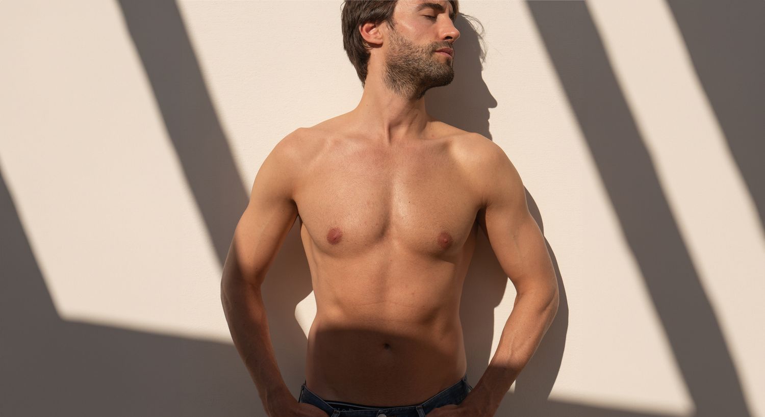 Shirtless man posing against a light background.